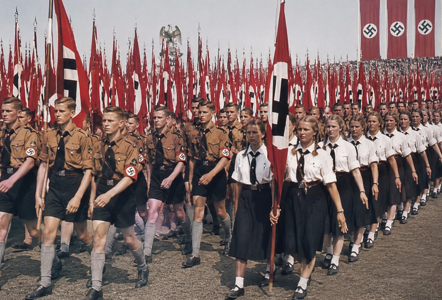 Groepen jongens en meisjes in uniform marcheren tijdens een bijeenkomst van de Hitlerjugend en de Bund Deutscher Mädel.