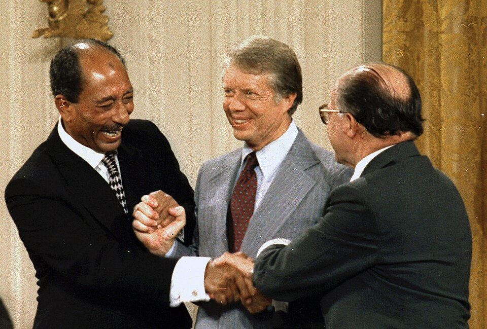 Anwar Sadat (Egypte), Jimmy Carter (VS) en Menachem Begin (Israël) bij de Camp David-akkoorden in 1978, https://commons.wikimedia.org/wiki/File:Anwar_Sadat_Jimmy_Carter_Menachem_Begin_sign_Camp_David_Accords-1978_(cropped).jpg